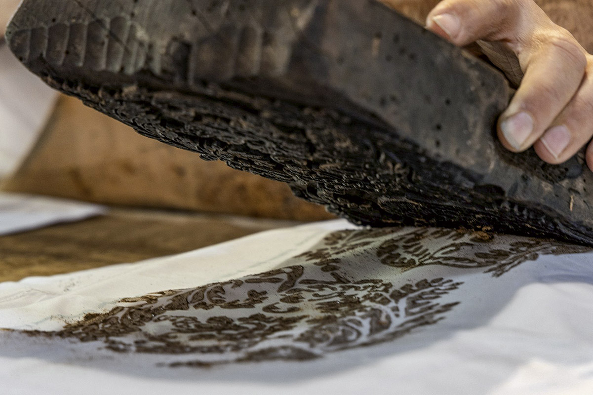 Lo stampo in legno di pero, dopo essere stato battuto sul tessuto, viene sollevato, lasciando il disegno impresso sul prodotto da realizzare